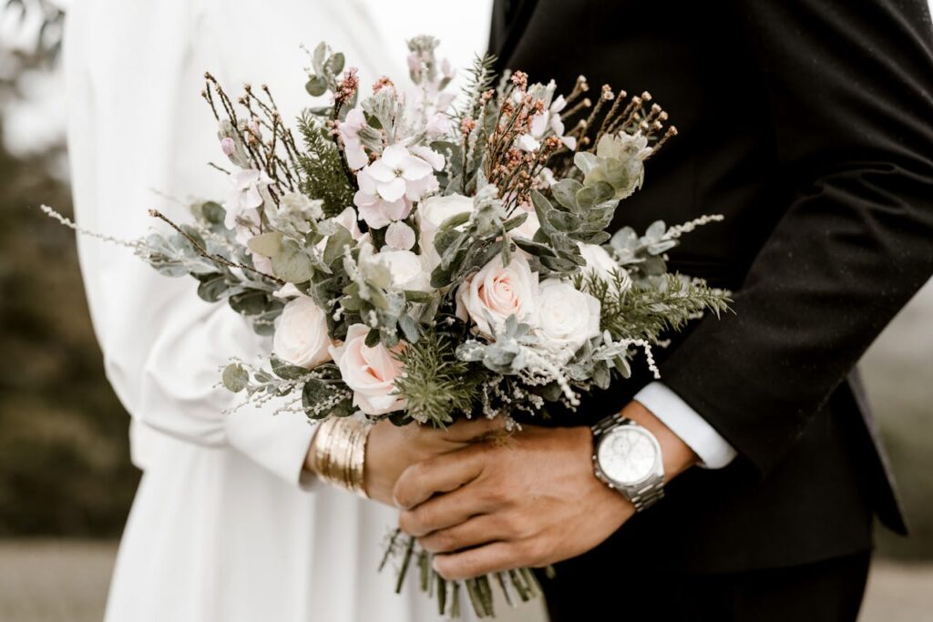 Close-up of a wedding bouquet held by bride and groom, showcasing romance and elegance.